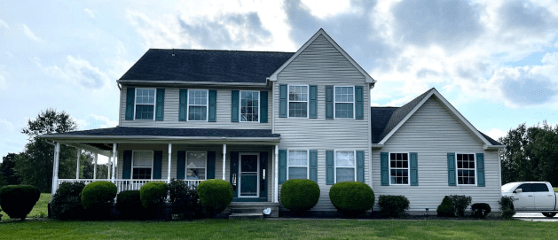 Spacious suburban two-story house with green shutters and large porch.