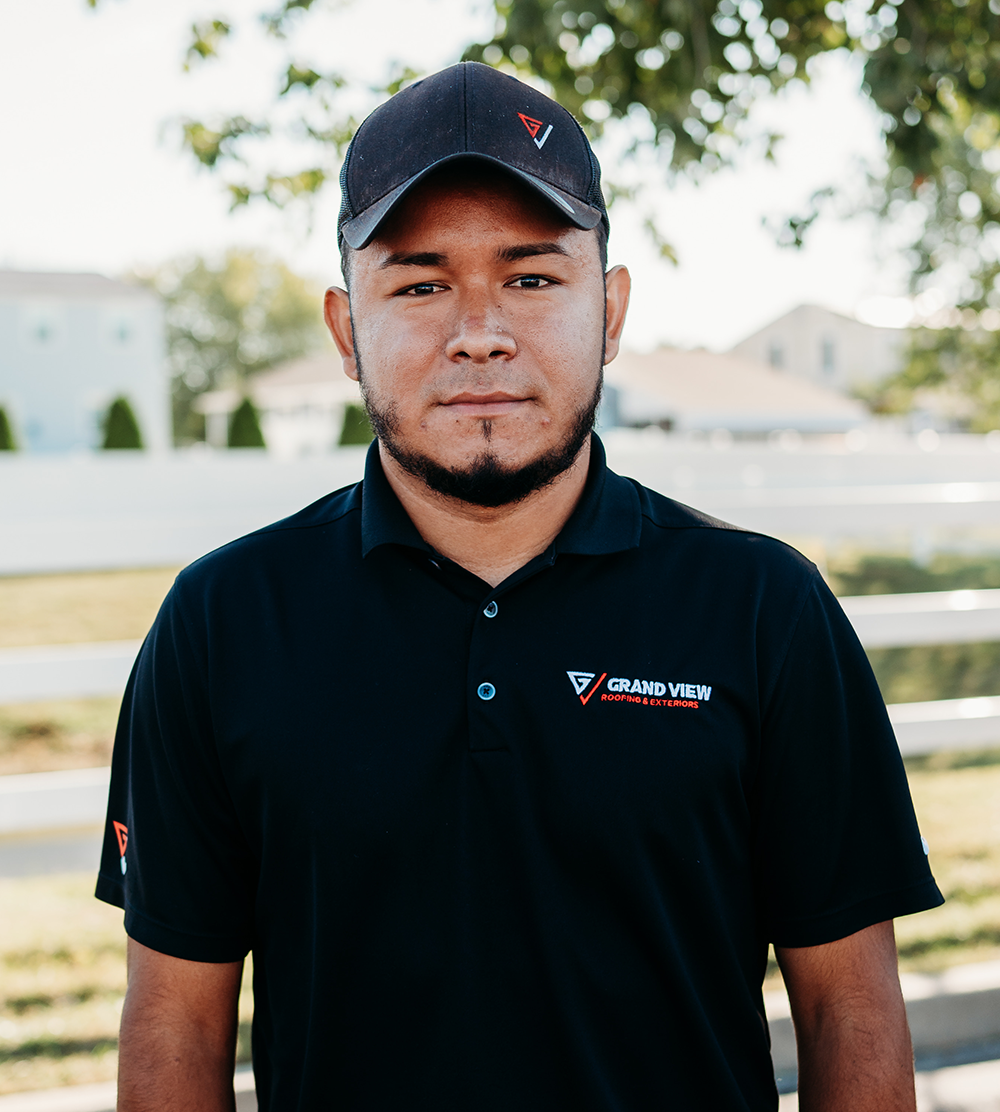 Professional man in Grand View Roofing & Exteriors polo shirt and cap outdoors