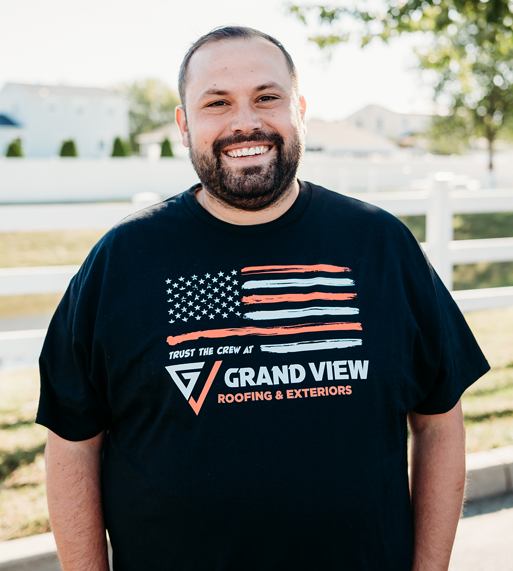 Smiling man in Grand View Roofing & Exteriors t-shirt with American flag design