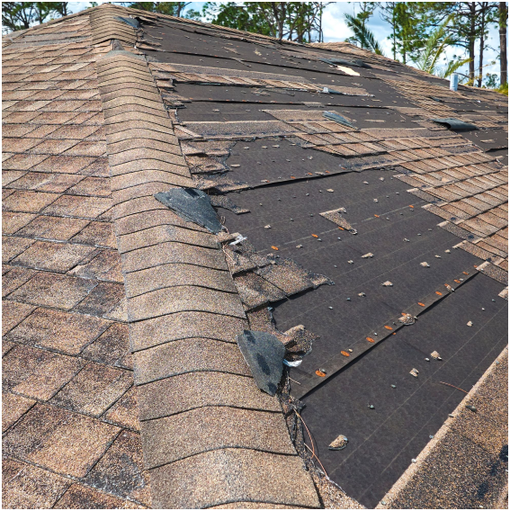 Damaged roof with missing shingles, highlighting storm damage.