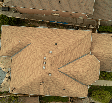 Aerial view of a large house with a beige shingle roof.