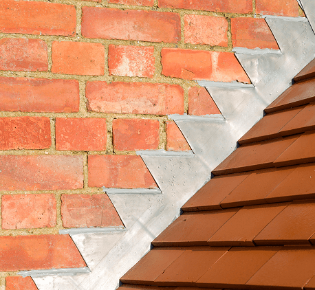 Brick wall with lead flashing and brown tiled roof intersection