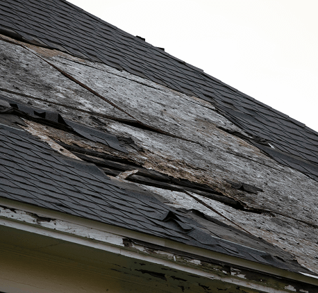 Close-up of a deteriorated roof with damaged and missing shingles.